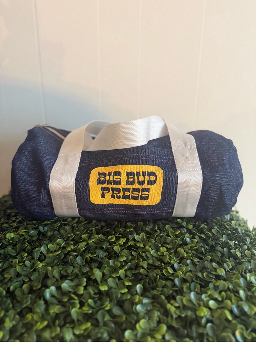 Big Bud Press navy duffel with white straps and yellow logo